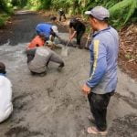 Foto warga sedang perbaiki jalan rusak.